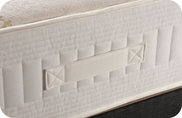 White quilted mattress with a fabric handle on the side for easy lifting.