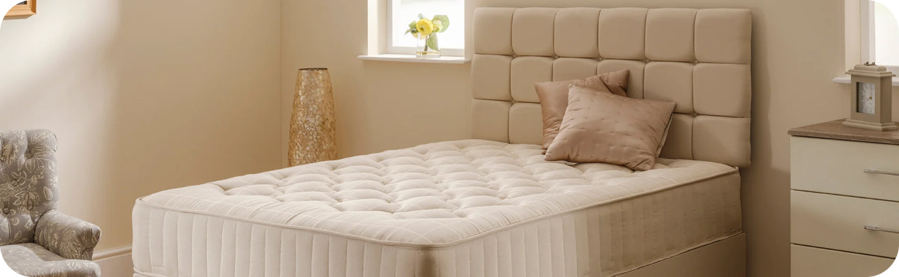 Beige upholstered mattress with tufted design on a neutral-toned bedroom set.