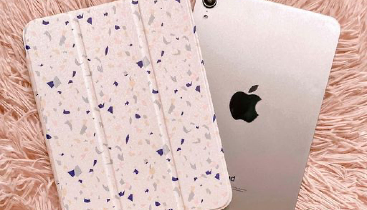 Speckled pink and purple iPad case with foldable cover next to a silver iPad.